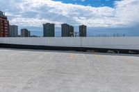 an empty parking lot with a large building in the background, in the foreground is cloudy skies