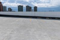 an empty parking lot with a large building in the background, in the foreground is cloudy skies