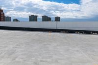 an empty parking lot with a large building in the background, in the foreground is cloudy skies