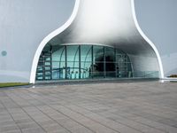 a very large modern building that is white and grey in color, with a clock attached to the side of it