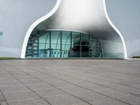 a very large modern building that is white and grey in color, with a clock attached to the side of it