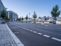 a long empty street is next to a large building that has an outdoor structure in the background