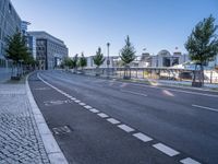 a long empty street is next to a large building that has an outdoor structure in the background