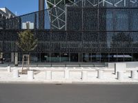 street scene in front of large building with modern architecture in back ground of sidewalk with benches to sit