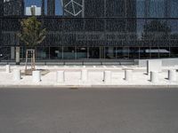 street scene in front of large building with modern architecture in back ground of sidewalk with benches to sit