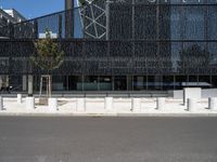 street scene in front of large building with modern architecture in back ground of sidewalk with benches to sit