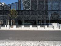 street scene in front of large building with modern architecture in back ground of sidewalk with benches to sit