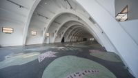 a picture of an arched hallway with painted carpets and arches on the floor with art