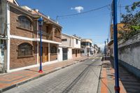 an empty street with parked cars and some buildings in the background at daytime with no clouds