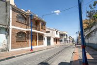 an empty street with parked cars and some buildings in the background at daytime with no clouds