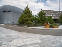 a round sidewalk with potted plants in front of it and buildings next to it