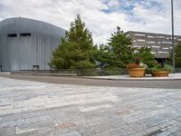 a round sidewalk with potted plants in front of it and buildings next to it