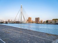 a bridge is over an empty city street with buildings in the background and the water