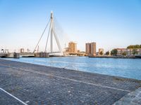 a bridge is over an empty city street with buildings in the background and the water