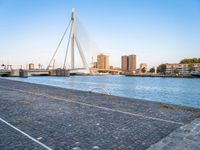 a bridge is over an empty city street with buildings in the background and the water