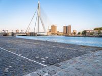 a bridge is over an empty city street with buildings in the background and the water