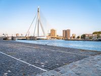 a bridge is over an empty city street with buildings in the background and the water