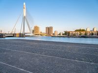 a bridge is over an empty city street with buildings in the background and the water