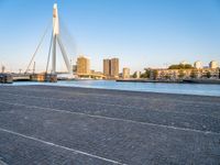 a bridge is over an empty city street with buildings in the background and the water