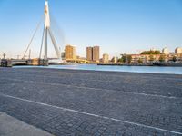 a bridge is over an empty city street with buildings in the background and the water