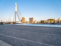 a bridge is over an empty city street with buildings in the background and the water