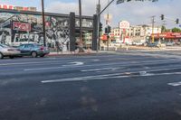 cars sit on the street as it goes through the city streets, with an advertising ad in the background