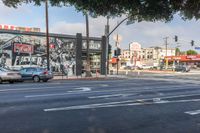 cars sit on the street as it goes through the city streets, with an advertising ad in the background