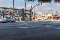 cars sit on the street as it goes through the city streets, with an advertising ad in the background