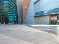 an empty sidewalk near large, modern buildings and a walkway leading to it that leads down to the center