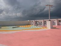 a sky view of a parking lot with buildings in the background and clouds over it