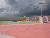 a sky view of a parking lot with buildings in the background and clouds over it