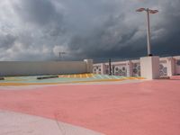 a sky view of a parking lot with buildings in the background and clouds over it