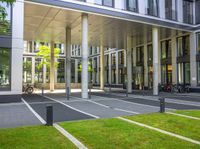 a building is shown with large columns and many bicycles parked outside the front door area