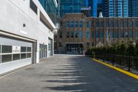 the sidewalk in front of the large buildings has yellow border on it to a black fence