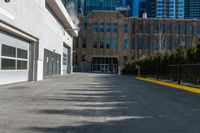 the sidewalk in front of the large buildings has yellow border on it to a black fence