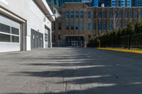 the sidewalk in front of the large buildings has yellow border on it to a black fence