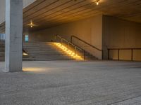 a stairway leading up to the top of a concrete building with stairs and a lit area for the light to enter