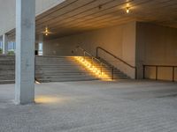 a stairway leading up to the top of a concrete building with stairs and a lit area for the light to enter