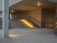 a stairway leading up to the top of a concrete building with stairs and a lit area for the light to enter