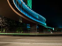 an illuminated pedestrian bridge is going over the street at night and passing by it at a curve