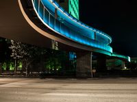 an illuminated pedestrian bridge is going over the street at night and passing by it at a curve