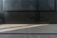 a black wall with some small pieces of metal on it that are covering it from sun