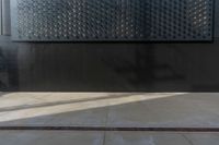 a black wall with some small pieces of metal on it that are covering it from sun