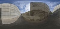 the distorted image shows a large concrete building that is surrounded by smaller concrete structures with a sky background