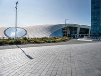 a long white curved building has two circular windows on the outside and a sidewalk on the outside