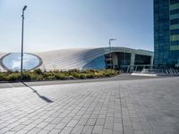 a long white curved building has two circular windows on the outside and a sidewalk on the outside