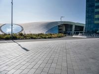 a long white curved building has two circular windows on the outside and a sidewalk on the outside