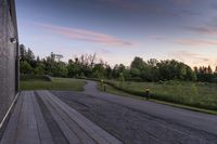 a paved pathway leading into the evening sun set and forest in background with dusk colors