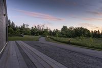 a paved pathway leading into the evening sun set and forest in background with dusk colors