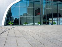 a large modern building is reflected by large glass windows and trees in the background's silhouette